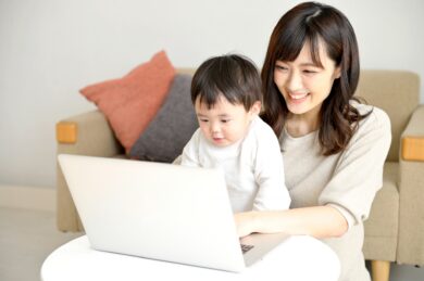 パソコンの前で作業する母親と赤ん坊